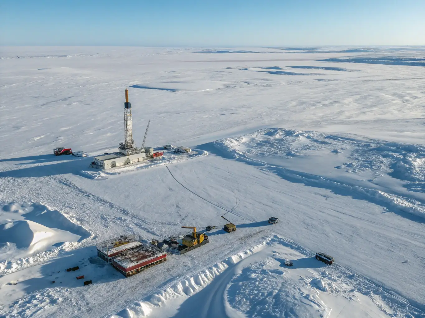 A high-quality photograph of specialized drilling equipment operating in a snowy Arctic landscape, with visible safety measures and environmental protection protocols in place.